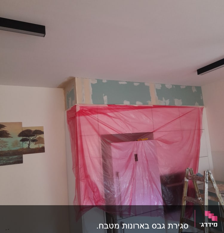 קיר עם טיח גבס, סולם ויריעת פלסטיק ורודה